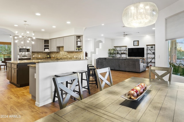 dining space with plenty of natural light, arched walkways, and wood finished floors