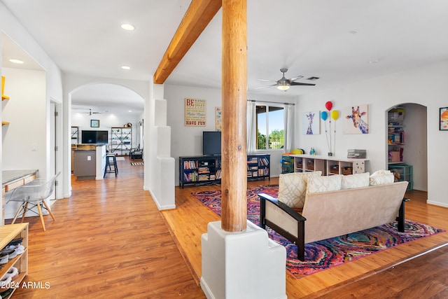 living room with arched walkways, recessed lighting, ceiling fan, light wood-type flooring, and beamed ceiling