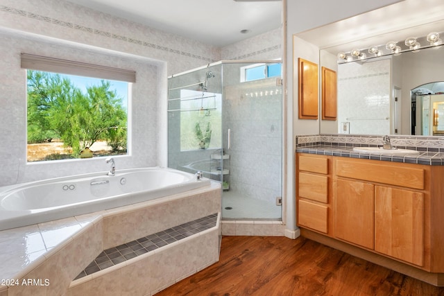 bathroom featuring a garden tub, a shower stall, wood finished floors, and vanity