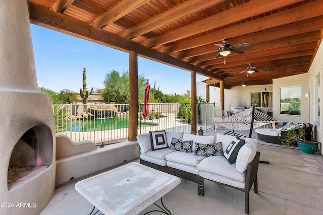 view of patio / terrace featuring an outdoor living space with a fireplace, fence, and ceiling fan