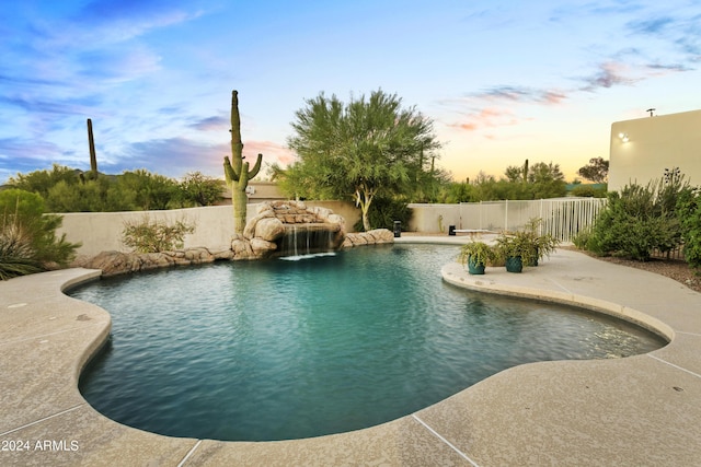 pool at dusk featuring a fenced backyard, a fenced in pool, and a patio