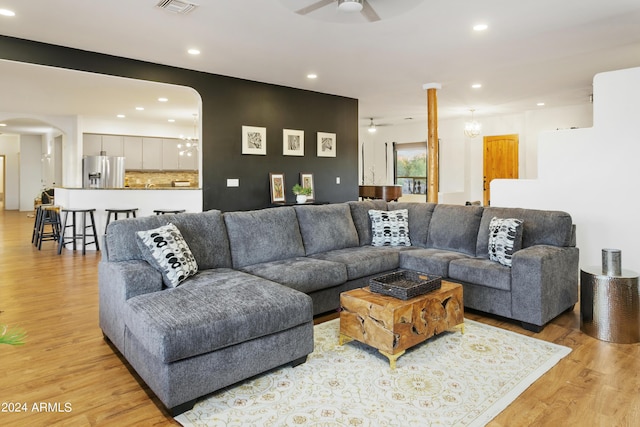 living room with light wood-style floors, recessed lighting, arched walkways, and ceiling fan with notable chandelier