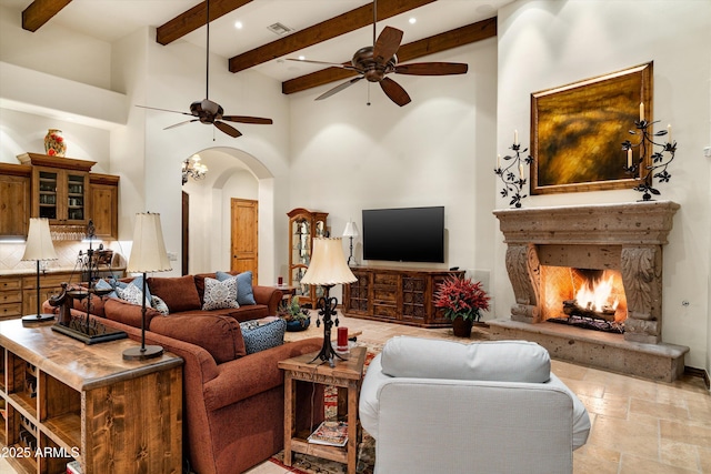 living room featuring ceiling fan, beamed ceiling, and a high ceiling