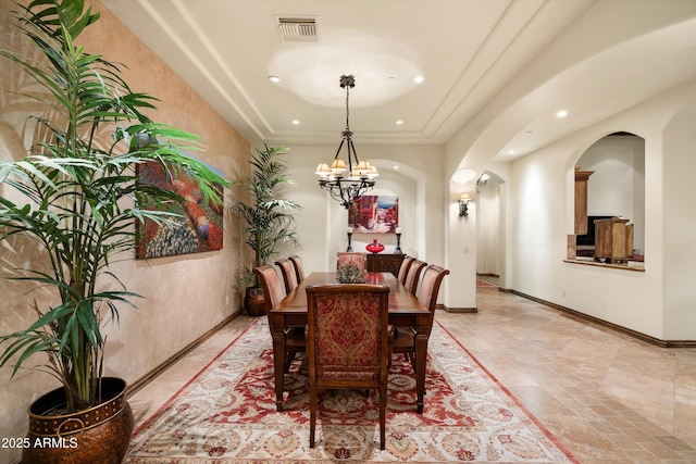 dining area with an inviting chandelier and a tray ceiling