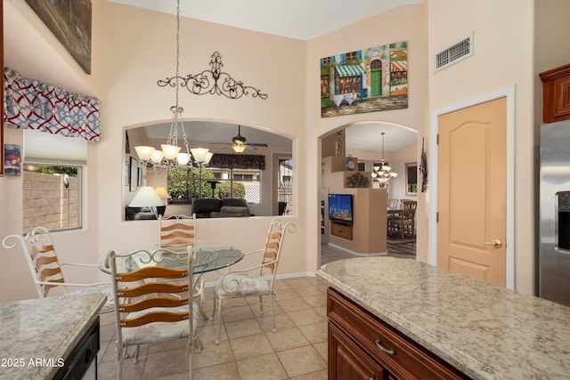 kitchen with arched walkways, a high ceiling, visible vents, and pendant lighting