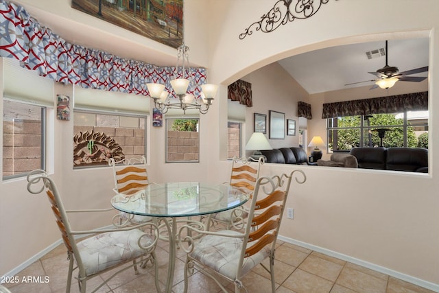 tiled dining room with arched walkways, ceiling fan with notable chandelier, visible vents, baseboards, and vaulted ceiling