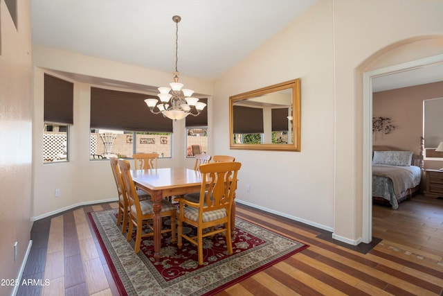 dining space featuring lofted ceiling, baseboards, wood finished floors, and a notable chandelier