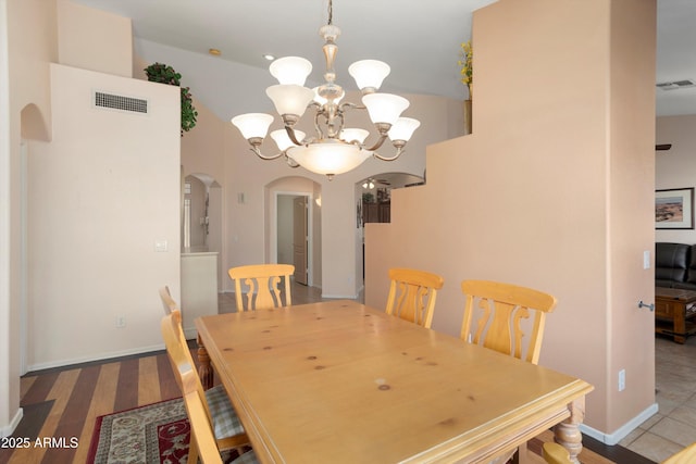 dining room featuring visible vents, arched walkways, a notable chandelier, and wood finished floors