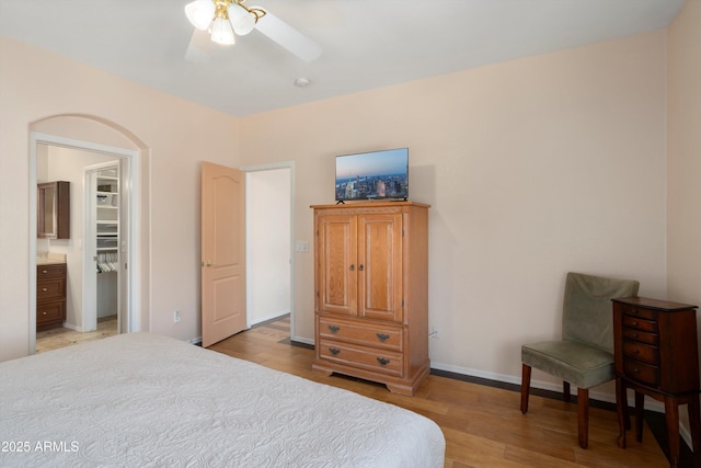 bedroom with light wood-style floors, a spacious closet, baseboards, and a ceiling fan