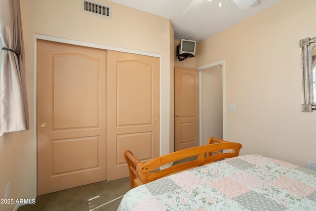 carpeted bedroom featuring ceiling fan, visible vents, and a closet