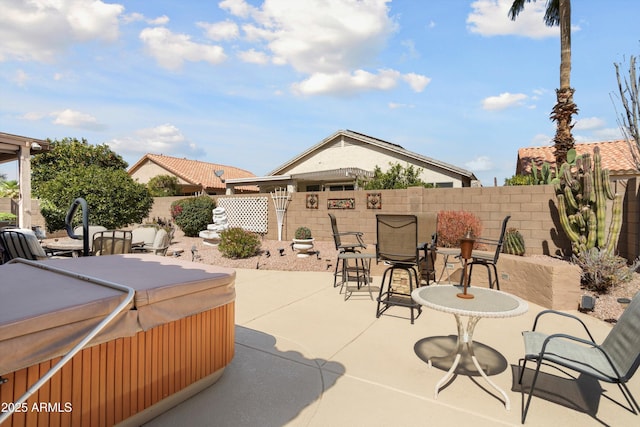 view of patio with a hot tub, a fenced backyard, and outdoor dining space