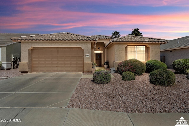 view of front of house with an attached garage, a tiled roof, concrete driveway, and stucco siding