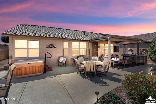 patio terrace at dusk with outdoor dining area, outdoor lounge area, and a hot tub