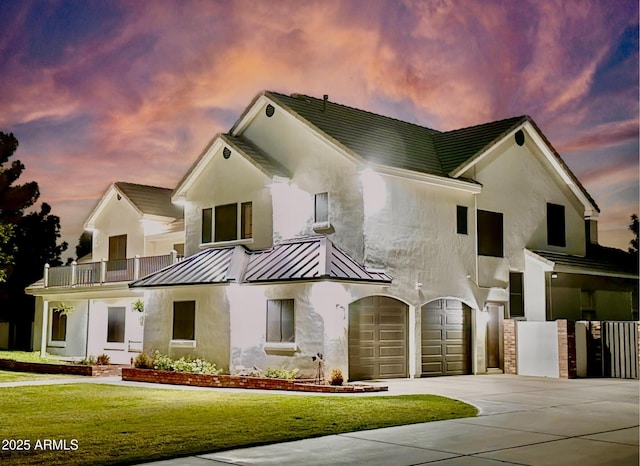 view of front facade with a front lawn, a standing seam roof, metal roof, concrete driveway, and a garage