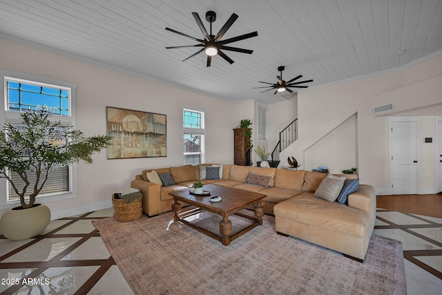 living area featuring stairs, baseboards, a ceiling fan, and crown molding