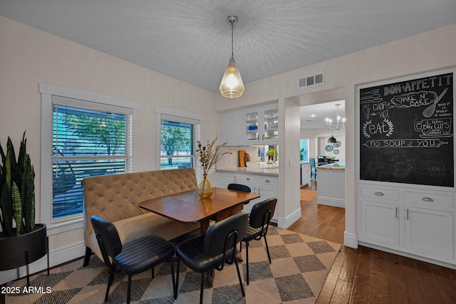 dining room featuring visible vents, baseboards, dark wood-type flooring, and an inviting chandelier