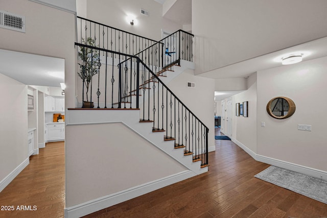 staircase with visible vents, baseboards, and hardwood / wood-style flooring