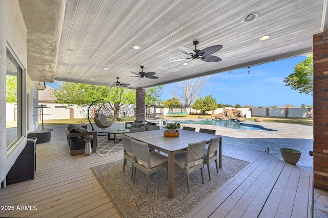 wooden deck featuring a fenced in pool, outdoor dining area, ceiling fan, and fence