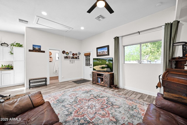 living area featuring attic access, wood finished floors, visible vents, and ceiling fan