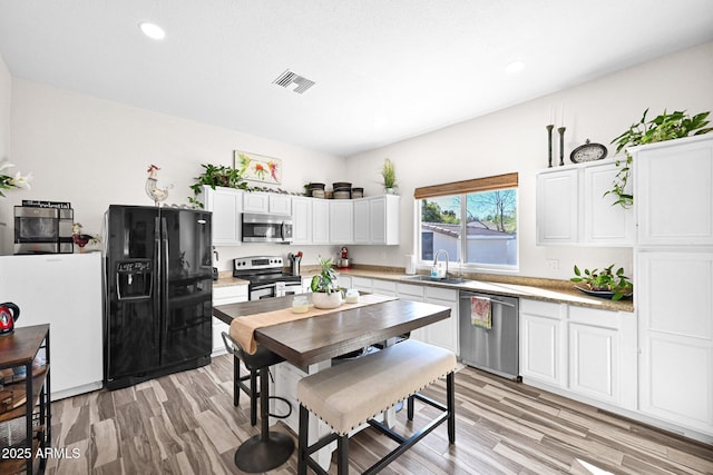 kitchen featuring a sink, visible vents, light wood-type flooring, and appliances with stainless steel finishes