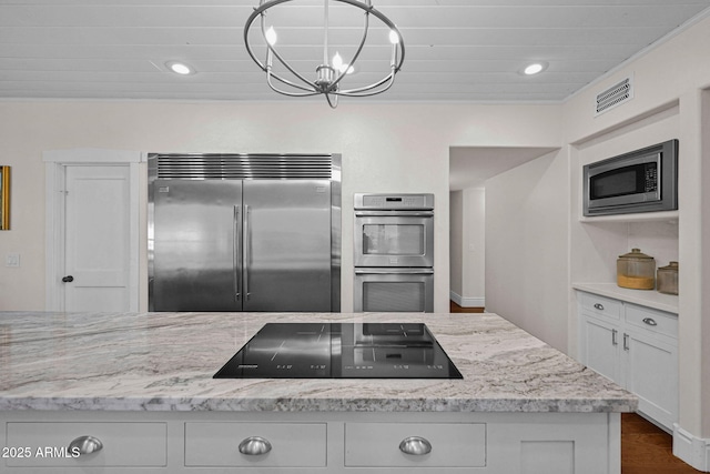 kitchen with built in appliances, white cabinets, visible vents, and light stone countertops