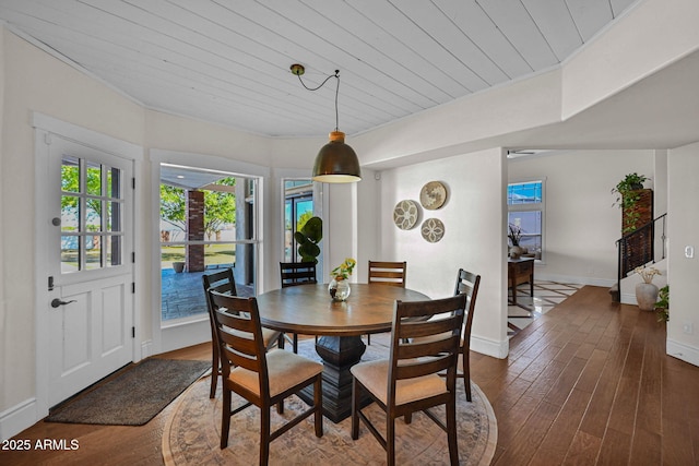 dining space featuring dark wood-style floors, wooden ceiling, and baseboards