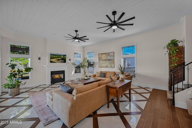 living area with a glass covered fireplace, wooden ceiling, crown molding, and baseboards