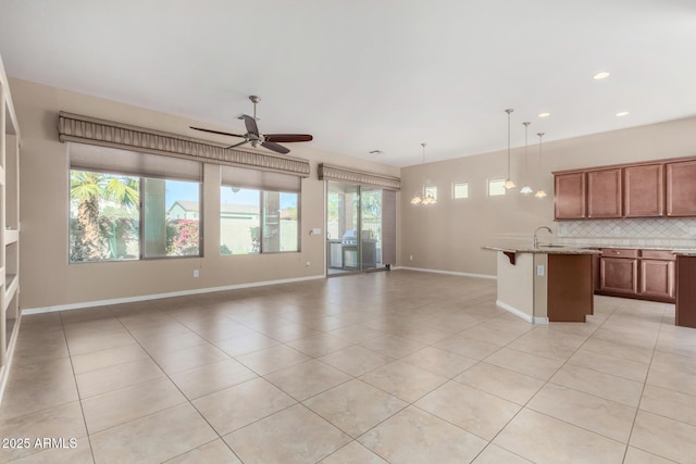 unfurnished living room featuring sink, light tile patterned flooring, and ceiling fan