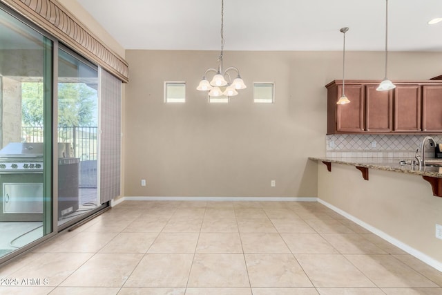 unfurnished dining area with sink, light tile patterned floors, and a notable chandelier