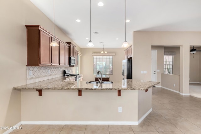 kitchen featuring sink, decorative light fixtures, kitchen peninsula, backsplash, and stainless steel appliances