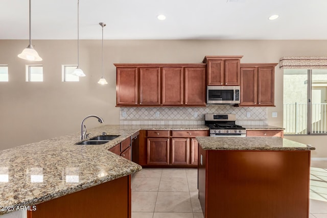 kitchen with appliances with stainless steel finishes, sink, hanging light fixtures, light tile patterned flooring, and light stone counters