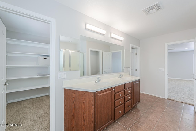 40232 W Marion May Ln, Maricopa, AZ 85138 - full bathroom featuring double vanity, a stall shower, tile patterned flooring, baseboards, and a walk in closet