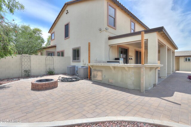40232 W Marion May Ln, Maricopa, AZ 85138 - back of house featuring a fire pit, an outdoor kitchen, a patio, stucco siding, and fence