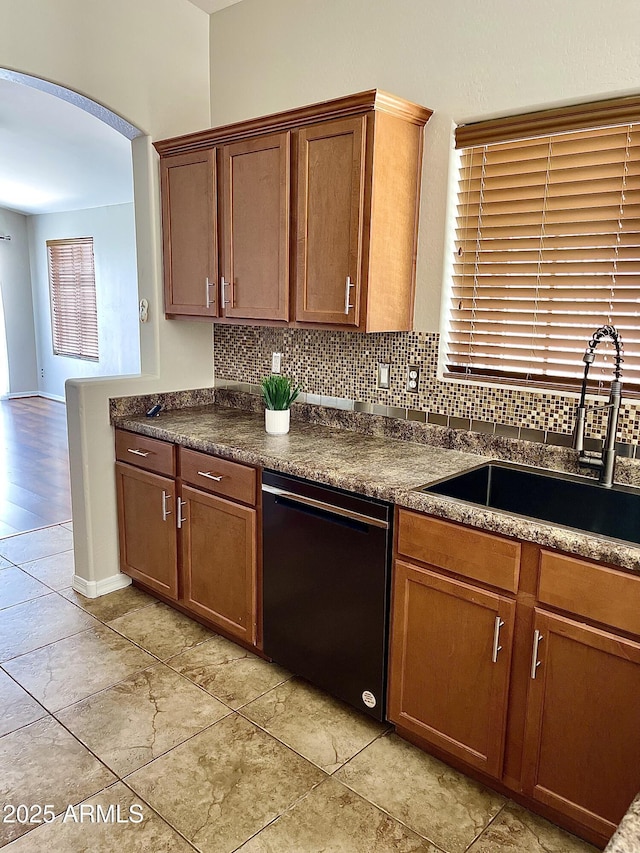 5749 S 247th Dr, Buckeye, AZ 85326 - kitchen with black dishwasher, a sink, arched walkways, dark countertops, and backsplash