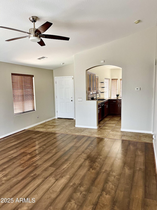 5749 S 247th Dr, Buckeye, AZ 85326 - unfurnished living room with ceiling fan, a sink, arched walkways, wood finished floors, and baseboards