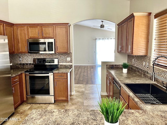 5749 S 247th Dr, Buckeye, AZ 85326 - kitchen featuring appliances with stainless steel finishes, a sink, arched walkways, ceiling fan, and backsplash