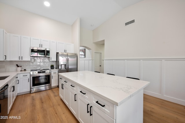1748 E Cortez Dr, Gilbert, AZ 85234 - kitchen with visible vents, a kitchen island, light wood-style floors, appliances with stainless steel finishes, and backsplash