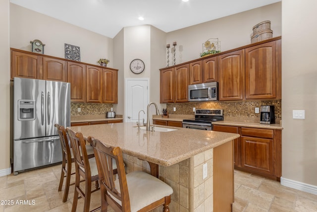 6870 S Justin Way, Chandler, AZ 85249 - kitchen featuring appliances with stainless steel finishes, a sink, baseboards, a kitchen island with sink, and light stone countertops