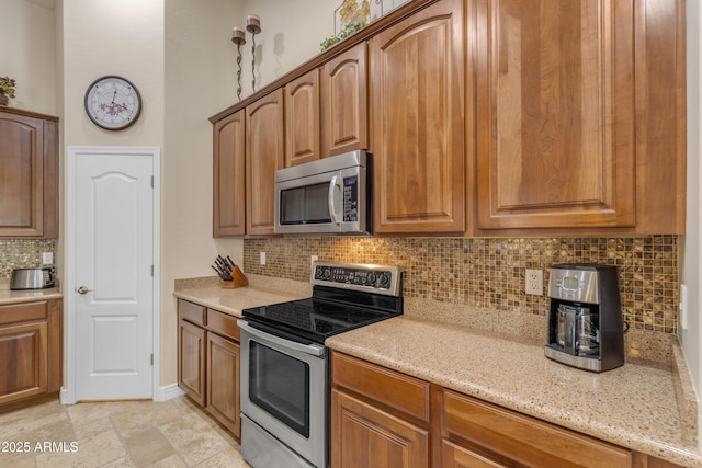 6870 S Justin Way, Chandler, AZ 85249 - kitchen with appliances with stainless steel finishes, tasteful backsplash, light stone counters, and brown cabinetry