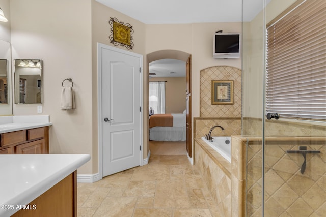 6870 S Justin Way, Chandler, AZ 85249 - bathroom featuring stone tile flooring, vanity, connected bathroom, tiled bath, and baseboards