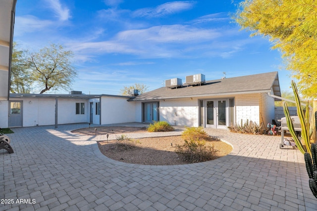 back of property featuring central air condition unit, french doors, and a patio