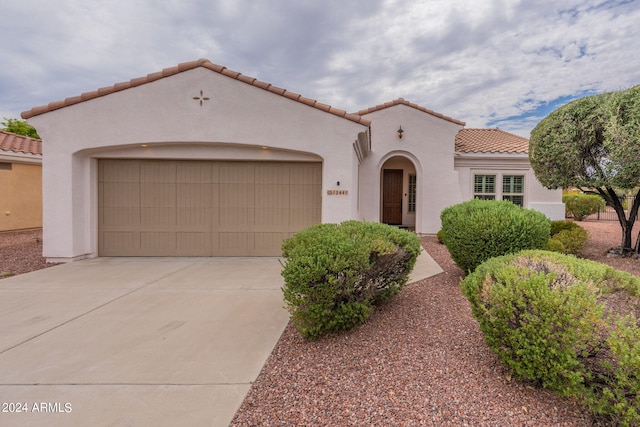 mediterranean / spanish house featuring concrete driveway, a tiled roof, an attached garage, and stucco siding