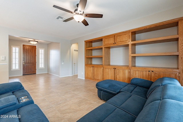 living area with baseboards, built in shelves, visible vents, and a ceiling fan