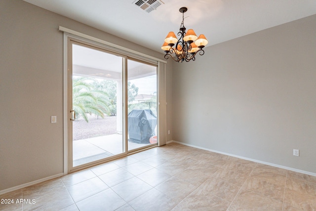 spare room with a chandelier, visible vents, and baseboards