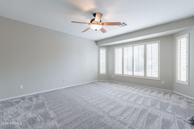 carpeted spare room with a ceiling fan, visible vents, and baseboards