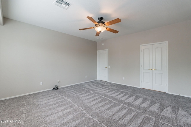 carpeted spare room with baseboards, visible vents, and a ceiling fan