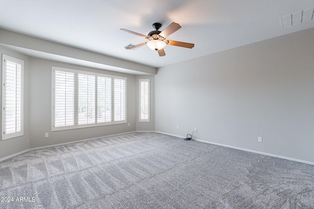 spare room with carpet floors, visible vents, ceiling fan, and baseboards