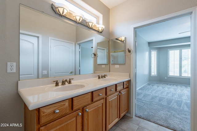 bathroom with baseboards, double vanity, a sink, and tile patterned floors