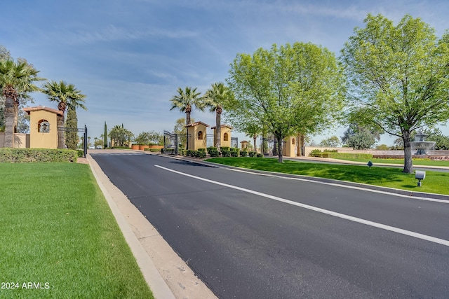 view of street featuring a gate, a gated entry, and curbs