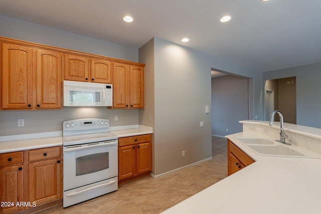 kitchen featuring recessed lighting, white appliances, light countertops, and a sink